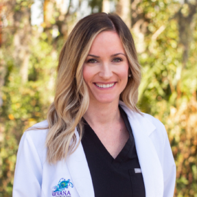 Member of the Nirvana Medical Spa Team, Kaylee stands in her white coat and black crubs